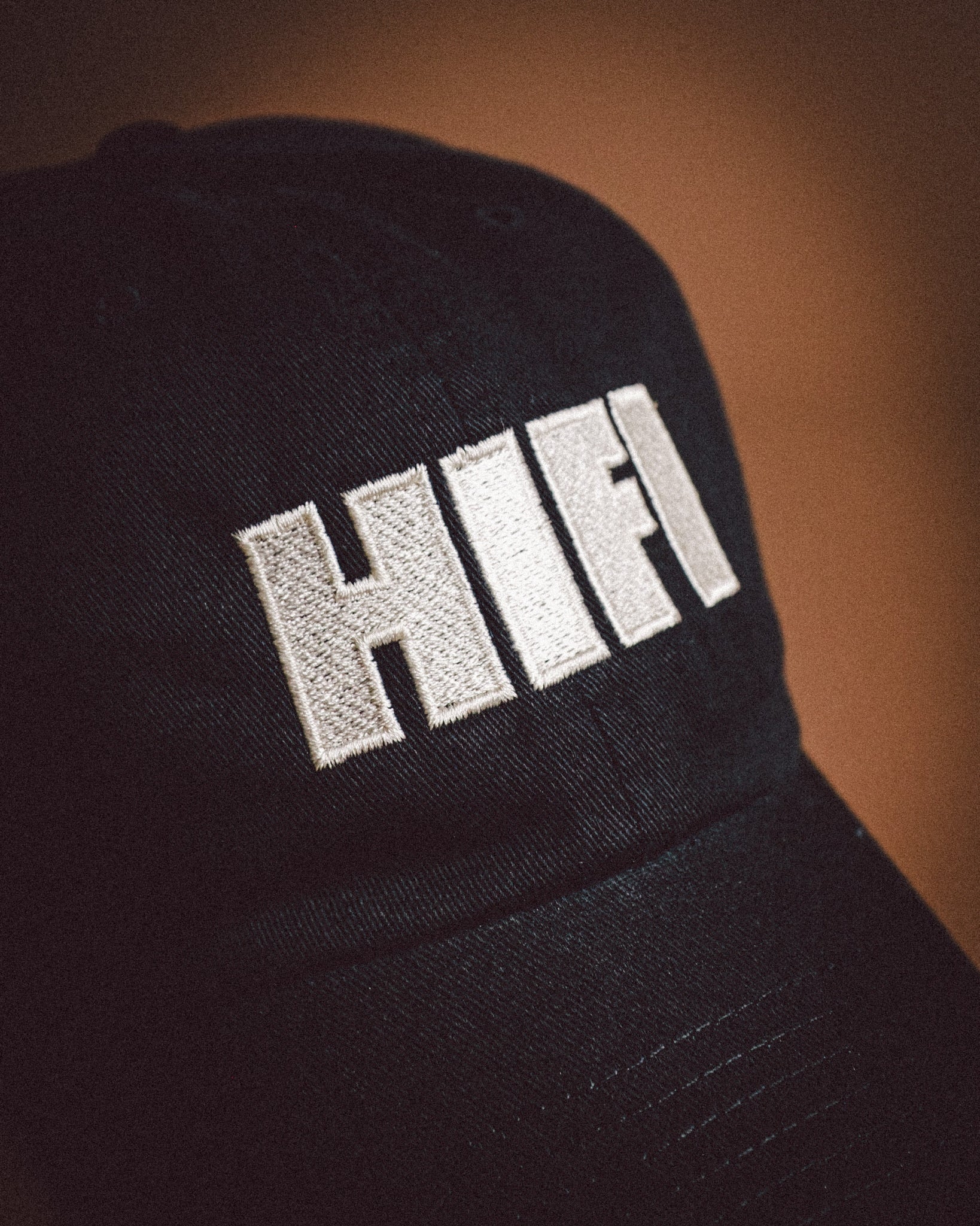 Black cap with 'HIFI' embroidered on it against a brown background