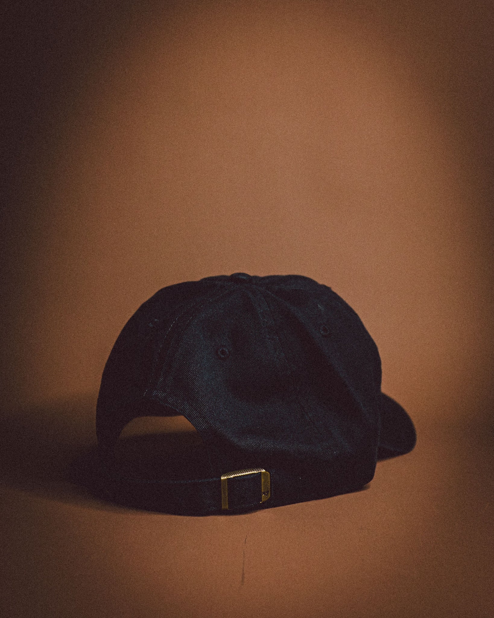 Black cap with a gold buckle on a brown background