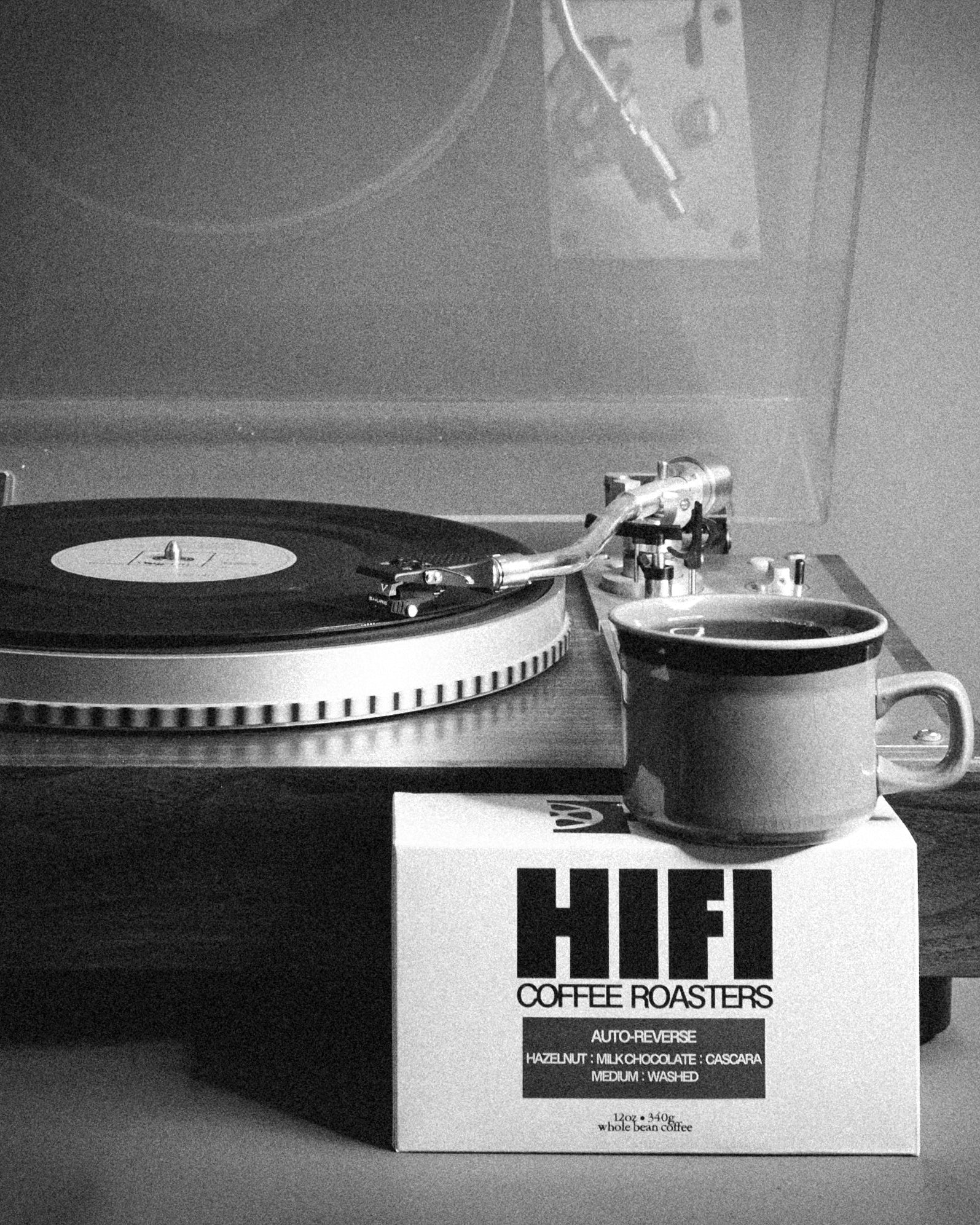 Turntable with a record and a mug on top of a 'HIFI Coffee Roasters' box.